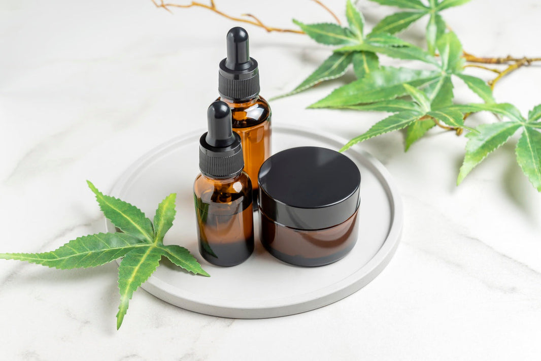 CBD products near hemp leaves on ceramic dish